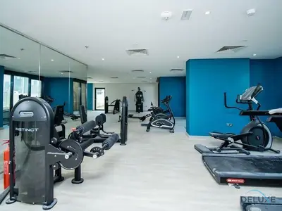 a gym with several treadmills and exercise bikes at Delightful Studio Apartment in Azizi Riviera 20, Al Merkadh by Deluxe Holiday Homes in Dubai
