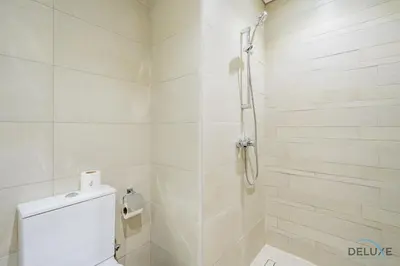 a white bathroom with a shower and a toilet at Delightful Studio Apartment in Azizi Riviera 20, Al Merkadh by Deluxe Holiday Homes in Dubai