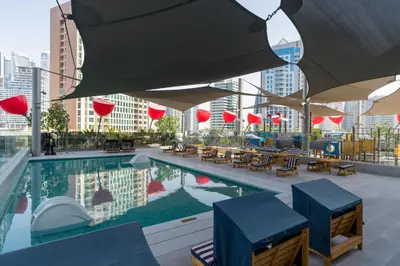 a swimming pool with tables and chairs on a building at Vacay Lettings - MAG -318 in Dubai