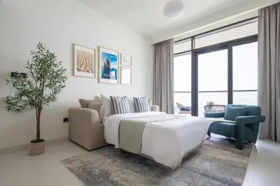 a white bedroom with a bed and a couch and a tree at Frank Porter - Marina Vista Tower 2 in Dubai