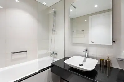 a white bathroom with a sink and a mirror at Spacious Studio in Business Bay in Dubai