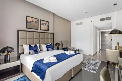 a bedroom with a large bed with blue and white pillows at Spacious Studio in Business Bay in Dubai