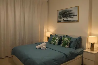 a bedroom with a bed with blue sheets and a tree at Bright and beautiful one bedroom apartment close to metro and beach in Dubai