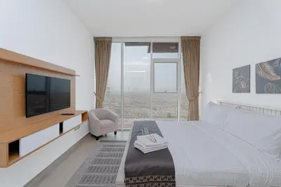 a bedroom with a bed with a television and a chair at Escape24 Cozy Studio with City View in JVC in Dubai