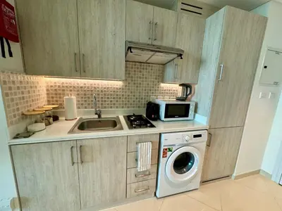 a kitchen with a sink and a washing machine at Hospitality Expert 7 Palm Studio - Beach Pool Bar in Dubai