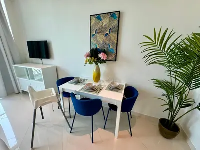 a dining room with a white table and blue chairs at Hospitality Expert 7 Palm Studio - Beach Pool Bar in Dubai