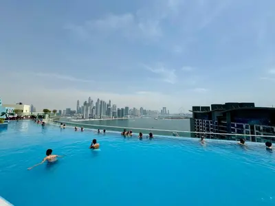 a group of people in a swimming pool with a city at Hospitality Expert 7 Palm Studio - Beach Pool Bar in Dubai
