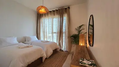a bedroom with two beds and a mirror and a window at Luxury 2BR Biophilic Retreat with Private Jacuzzi, Massage Chair & Infinity Pool in Dubai