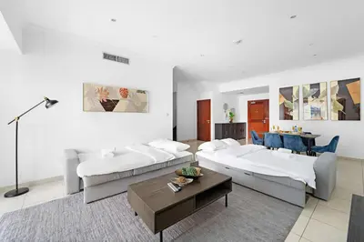 a living room with two beds and a table at FIRST CLASS 2BR Elite Urban Retreat in Dubai