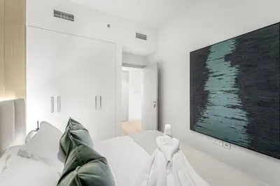 a white bedroom with a large tv on the wall at FIRST CLASS 3BR Trendy Urban Hideaway in Dubai