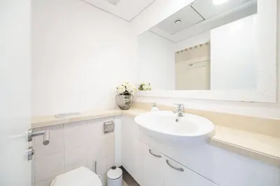 a white bathroom with a sink and a mirror at Marina Tower - Stunning 1BHK with Marina View by Elegant Escape's in Dubai