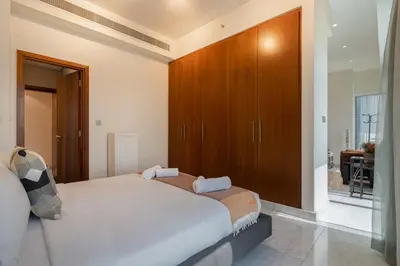 a bedroom with a bed and a wooden cabinet at Easy access to Metro - 1BR in Central Park, DIFC - Allsopp&Allsopp in Dubai