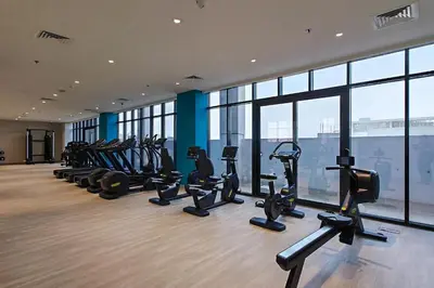 a gym with a bunch of treadms and elliptical machines at Pool View & 2 adults 2 kids & Brand New & Czechin in Dubai