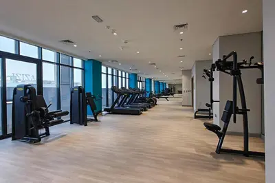 a gym with a row of treadmills and machines at Pool View & 2 adults 2 kids & Brand New & Czechin in Dubai