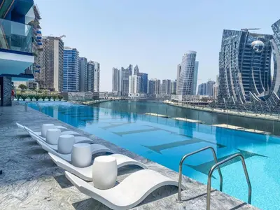 a swimming pool with white lounge chairs in a city at Elegant Studio in Binghatti Canal in Dubai