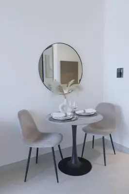 a table with two chairs and a mirror on the wall at Elegant Studio in Binghatti Canal in Dubai