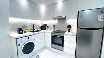 a white kitchen with a refrigerator and a washer at Dubai Marina - 1BHK Modish Apartment in Dubai