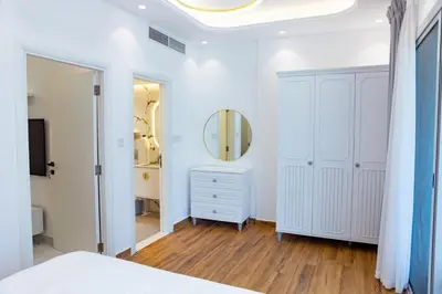 a white bedroom with a mirror and a dresser at Dubai Marina - 1BHK Modish Apartment in Dubai