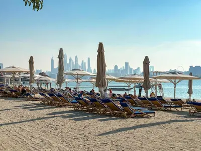 a group of chairs and umbrellas on a beach at Elegantly Renovated 1BR Apartment at 5 Star Resort in Dubai