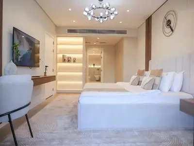 a bedroom with a large white bed and a chandelier at Stunning Renovated 1BR Apartment at 5 Star Resort in Dubai