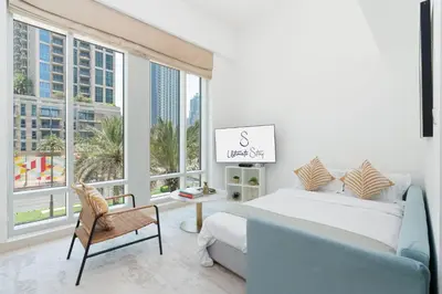 a bedroom with a bed and a chair and windows at New Ultimate Stay 5 min walk from Dubai Mall Lofts Tower 5 pax in Dubai