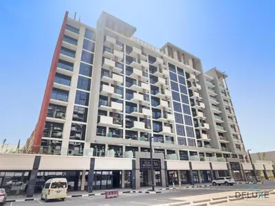 a large building on a street with a bus at Inviting Studio Apartment at Azizi Riviera 36 in Al Merkadh by Deluxe Holiday Homes in Dubai