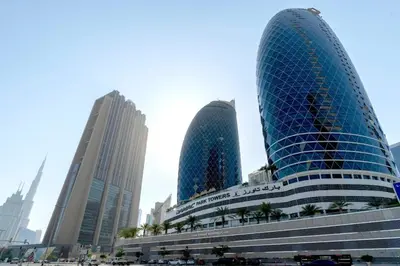 two tall buildings in a city with cars in front at Comfy Studio Apartment in DIFC in Dubai