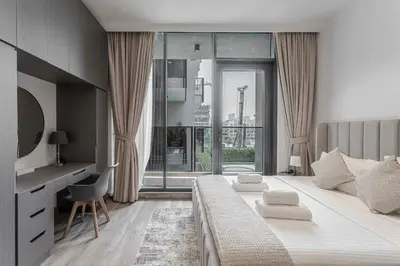 a bedroom with a large bed with a desk and a window at Modern Studio with Pool View & Gym Access in Dubai
