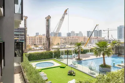a view of a pool with cranes in the city at Modern Studio with Pool View & Gym Access in Dubai