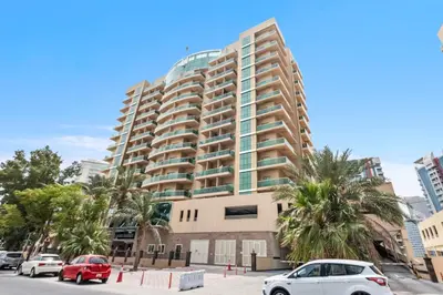 a tall building with cars parked in a parking lot at New Studio in Sport City - Pool, Gym, Parking in Dubai