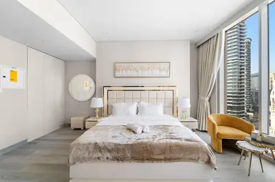 a white bedroom with a large bed and a chair at FIRST CLASS Studio Luxe Serenity Retreat in Dubai