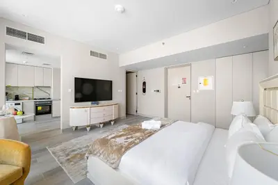 a white bedroom with a large bed and a tv at FIRST CLASS Studio Luxe Serenity Retreat in Dubai