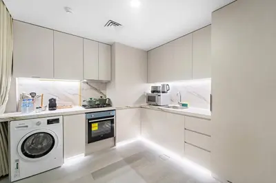 a kitchen with white cabinets and a washer and dryer at FIRST CLASS Studio Luxe Serenity Retreat in Dubai