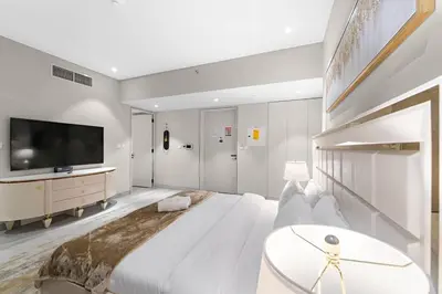 a white bedroom with a large bed and a tv at FIRST CLASS Studio Luxe Serenity Retreat in Dubai
