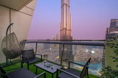 a balcony with chairs and tables and a view of a city at Luxury 4BR Flat, Downtown Dubai, Pool, Gym, PS5, Sleeps 11 Guests in Dubai