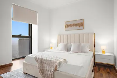 a white bedroom with a large bed and a large window at Luxury 4BR Flat, Downtown Dubai, Pool, Gym, PS5, Sleeps 11 Guests in Dubai