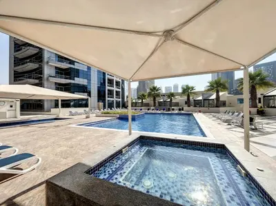 an outdoor swimming pool with an umbrella on a building at Bay Central 2 - Charming One Bedroom in Dubai