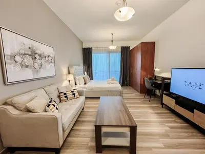 a living room with a couch and a bed and a television at Rare Holiday Homes - Lake View - The Crescent Tower - Dubai Production City - R1611 in Dubai