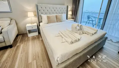 a bedroom with a large white bed with a chair at Rare Holiday Homes - Lake View - The Crescent Tower - Dubai Production City - R1611 in Dubai