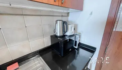 a coffeemaker sitting on top of a counter in a kitchen at Rare Holiday Homes - Lake View - Near Me'aisem City Centre - The Crescent Tower A - Dubai Production City - R910 in Dubai