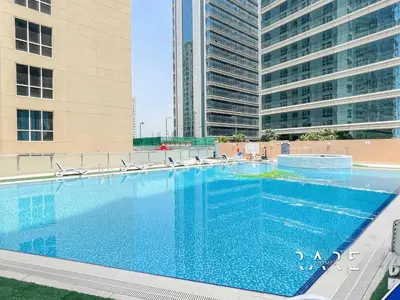 a large swimming pool in front of two tall buildings at Rare Holiday Homes - Lake View - Near Me'aisem City Centre - The Crescent Tower A - Dubai Production City - R910 in Dubai