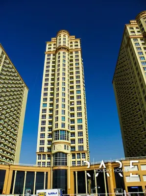 a tall building with a blue sky in the background at Rare Holiday Homes - Near The Lake - Lago Vista B - Dubai Production City - IMPZ - R2112 in Dubai