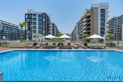 a large swimming pool with chairs and umbrellas at Comfortable Studio in Azizi Riviera 24, Al Merkadh by Deluxe Holiday Homes in Dubai