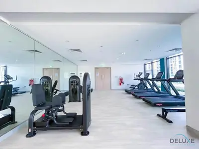 a gym with a row of treadmills and ellipticals at Comfortable Studio in Azizi Riviera 24, Al Merkadh by Deluxe Holiday Homes in Dubai