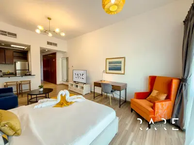 a bedroom with a bed and a chair and a kitchen at Rare Holiday Homes - Mediterranean Cluster - Near Ibn Battuta Mall - Discovery Garden - Building# Med 49 - R514 in Dubai