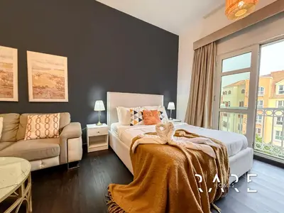 a bedroom with a bed and a couch and a window at Rare Holiday Homes - Mediterranean Cluster - Near Ibn Battuta Mall - Discovery Garden - Building# Med 49 - R411 in Dubai