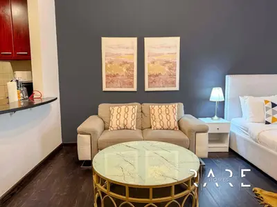 a living room with a couch and a glass table at Rare Holiday Homes - Mediterranean Cluster - Near Ibn Battuta Mall - Discovery Garden - Building# Med 49 - R411 in Dubai
