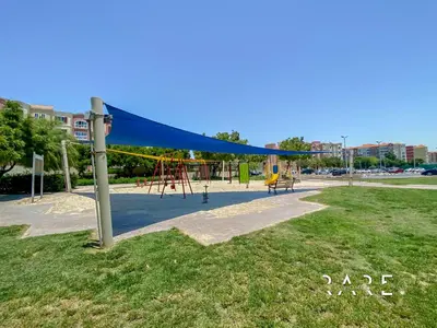 a playground in a park with a blue canopy at Rare Holiday Homes - Mediterranean Cluster - Near Ibn Battuta Mall - Discovery Garden - Building# Med 49 - R106 in Dubai