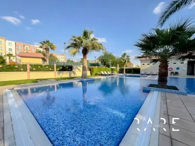 a swimming pool in a resort with palm trees at Rare Holiday Homes - Mediterranean Cluster - Near Ibn Battuta Mall - Discovery Garden - Building# Med 79 - R203 in Dubai