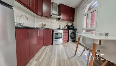 a kitchen with red cabinets and a sink and a table at Rare Holiday Homes - Mediterranean Cluster - Near Ibn Battuta Mall - Discovery Garden - Building# Med 79 - R203 in Dubai